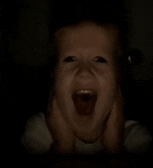 a baby screams in the dark with his mouth open