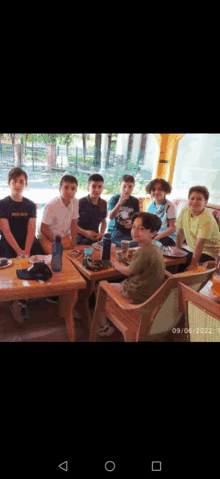 a group of young boys are sitting around a table with plates of food and drinks