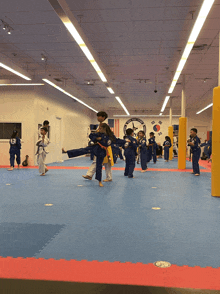 a group of kids are practicing martial arts in a gym with a clock on the wall