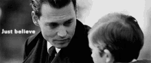 a black and white photo of a man in a suit and tie talking to a child .