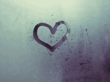 a heart is drawn on a window with rain drops