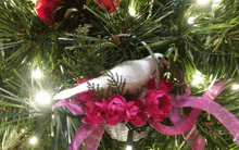 a christmas tree with a bird in a basket with pink flowers