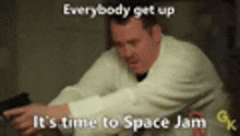 a man in a white coat is sitting at a table with the words " everybody get up it 's time to space jam "