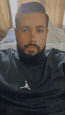 a man with a beard is wearing a black air jordan sweatshirt