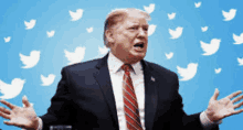 a man in a suit and tie is standing in front of a blue background with twitter birds flying around him .