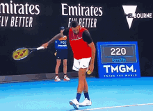 a man holding a tennis racquet on a tennis court in front of a sign that says 220 km / h