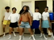 a group of men are dancing together in a room while wearing shorts and socks .