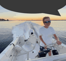 a boy in sunglasses is steering a boat