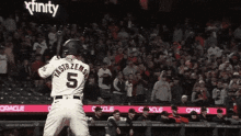 a baseball player with the number 5 on his back getting ready to bat