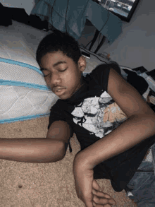 a young boy is laying on the floor next to a bed .