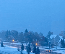 a car is driving down a snowy street in a residential neighborhood