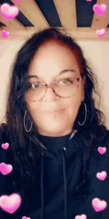 a woman wearing glasses and hoop earrings with pink hearts surrounding her