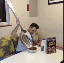 a man pouring cocoa pebbles into a bowl next to a carton of milk