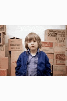 a boy in a blue jacket stands in front of a stack of boxes including one that says willapoint minced clams