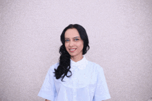 a woman wearing a white shirt with a lace collar smiles