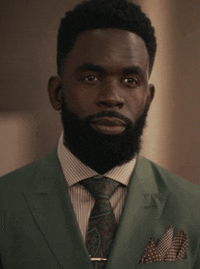 a man with a beard wearing a green suit