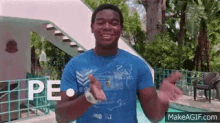 a man in a blue shirt is standing in front of a pool with the word peace written on his shirt