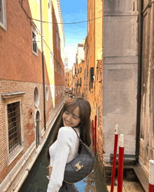 a woman stands in a narrow alley next to a sign that says " gondola "