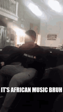 a man wearing a shirt that says just do it is sitting on a couch