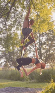 a man and a woman are performing aerial acrobatics on a rope