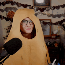 a woman wearing glasses and a peanut costume stands in front of a sign that says it 's a peanut