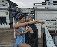 a man and a woman are hugging on a dock with a sign that says ' emergency ' on it