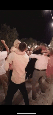 a group of people are dancing at a wedding reception at night .