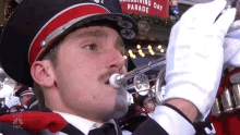 a man in a marching band is playing a trombone in front of a sign that says thanksgiving day parade