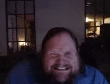 a man with a beard is making a funny face in front of a computer screen .