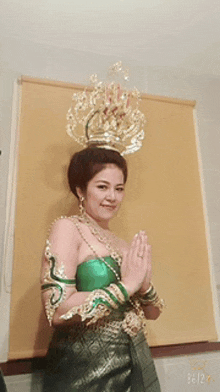 a woman wearing a green dress and a gold crown