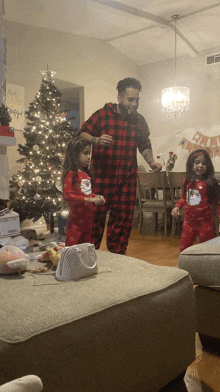 a man in a plaid pajamas is dancing with two little girls