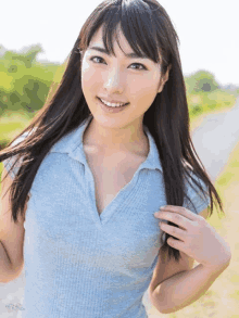 a woman in a blue shirt smiles for the camera