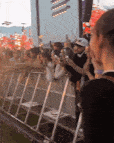 a crowd of people standing behind a fence with a man wearing a black shirt that says ' a '