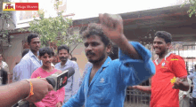 a man in a blue shirt is being interviewed by a man in a red shirt with telugu movies written on the bottom