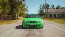 a green bmw with the license plate 330 bbl is driving down a road