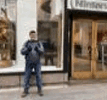 a man is standing in front of a store with a tablet in his hand .