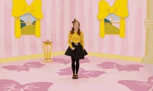 a girl in a yellow shirt and black skirt is dancing in a room