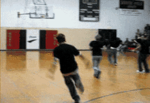 a group of people are running on a basketball court with a sign on the wall that says brooklyn high school