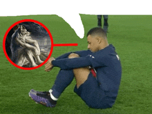 a soccer player is sitting on the grass with a picture of a wolf in the background