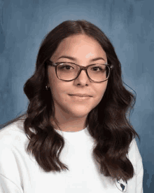 a young woman wearing glasses and a white shirt is taking a portrait .