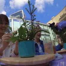 two women sit at a table with flowers and drinks and one of them is wearing a shirt that says love