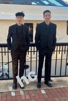 two men in suits are standing next to each other with a sign that says " no " in front of them