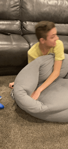 a man in a yellow shirt is laying on a bean bag chair in front of a couch