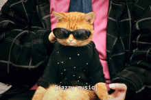 a cat wearing sunglasses and a black sweater is being held by a person with the words jazzy music below it