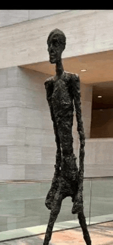 a statue of a man with long legs is standing in a room .