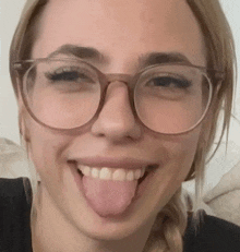 a woman wearing glasses is sticking her tongue out .