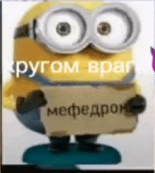 a minion with big eyes is holding a sign that says `` mefedron '' .