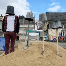 a man wearing a bucket on his head is standing next to a pile of sand