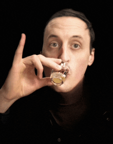 a man drinking from a shot glass with his hand