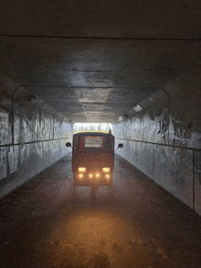 a scooter is driving through a tunnel with graffiti on the wall